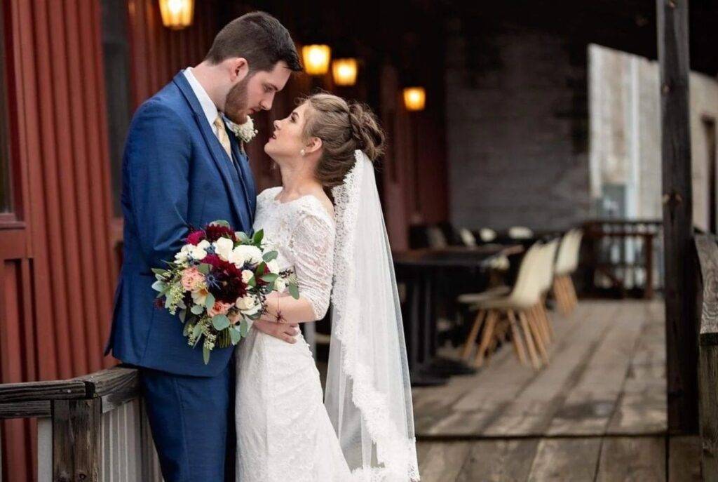 Bride and groom embracing on the outdoor deck of a rustic Bangor MI wedding venue.