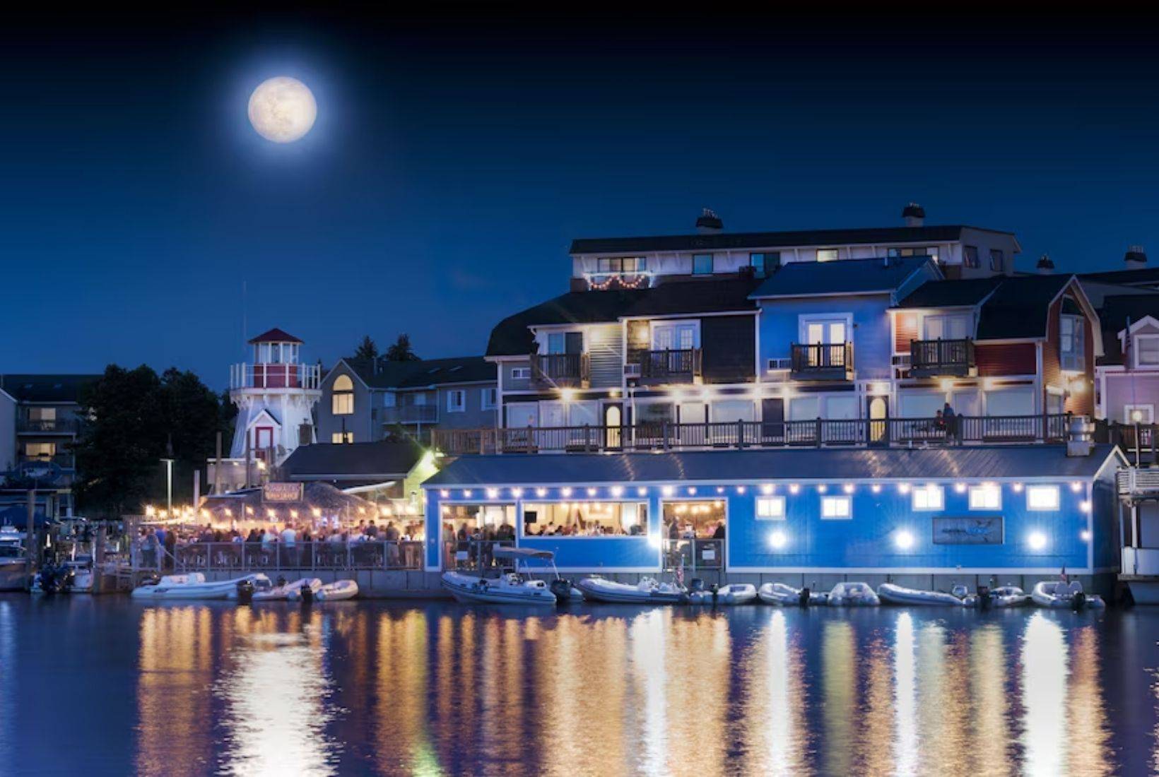 Bangor MI wedding venue. Waterfront resort at night with glowing lights and a full moon, showcasing lodging and travel near Bangor, MI.