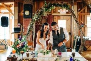 Lake Michigan Wedding, Mill Hall wedding venue cake cutting under a rustic arch inside a historic grain mill wedding venue in Michigan