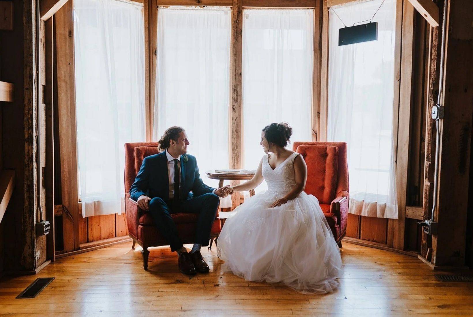 Grain Mill Wedding. Mill Hall wedding venue bride and groom seated together inside a historic grain mill wedding venue in Michigan
